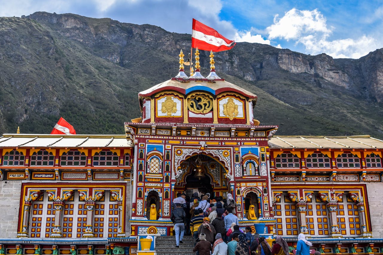 Services Vibrant view of Shree Badrinath Temple with pilgrims gathered around, set against a mountainous backdrop.