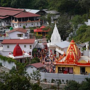 A vibrant aerial shot of the famous Kainchi Dham Temple complex surrounded by lush greenery in Uttarakhand.